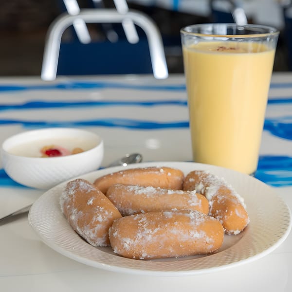 A plate of sweet pastries, a glass of mango lassi, and a bowl of rice pudding.
